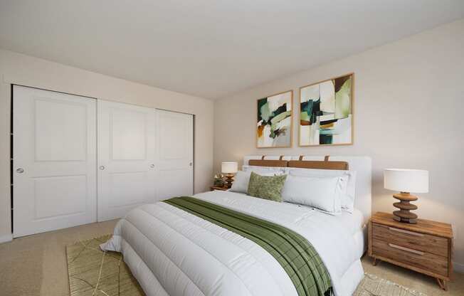 a bedroom with a white bed and two paintings on the wall at Rush River Apartments, Sacramento, CA, 95831