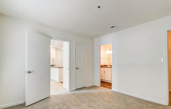 A white room with a carpet and a door leading to another room.
