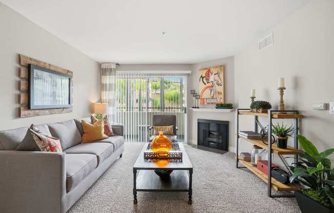 A living room with a grey couch, a coffee table, a fireplace, and a painting on the wall.