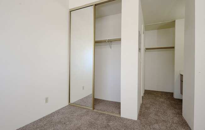 a bedroom with white walls and a carpeted floor at Park Columbia Apts, California