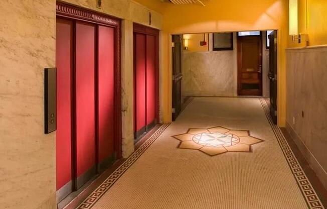 A hallway with red doors and a light on the floor.