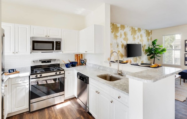 a white kitchen with stainless steel appliances and marble counter tops at Residences at Stevens Pond, Saugus, Massachusetts 01906