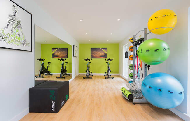 a home gym with green walls and hardwood flooring