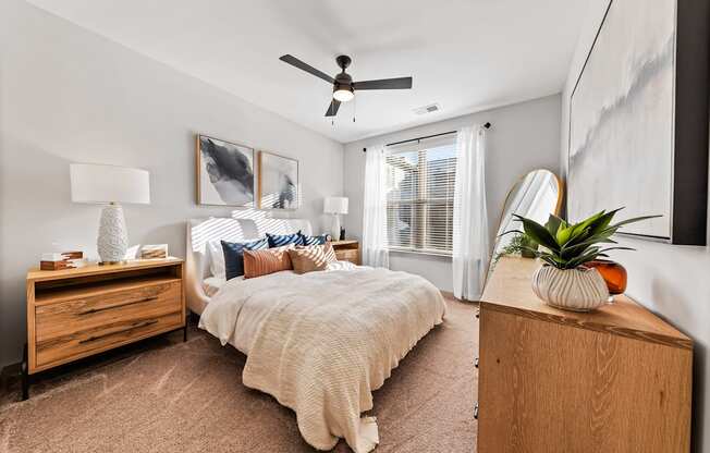 A bedroom with a bed, dresser, and ceiling fan