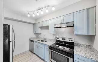A kitchen with a black refrigerator and a granite countertop.