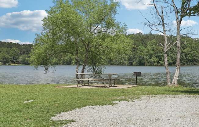 A picnic table sits on a gravel area next to a lake.