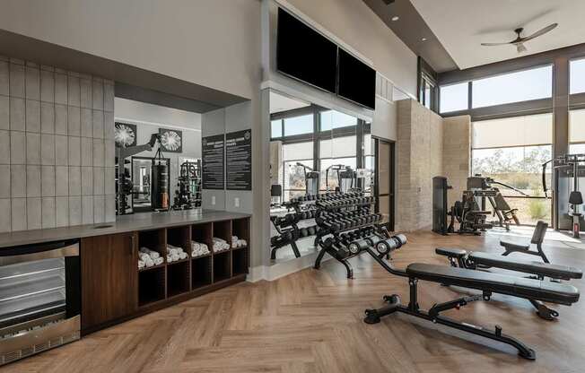 A gym with a variety of equipment including dumbbells, benches, and weights.