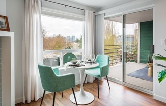 a living room with a table and chairs and a balcony