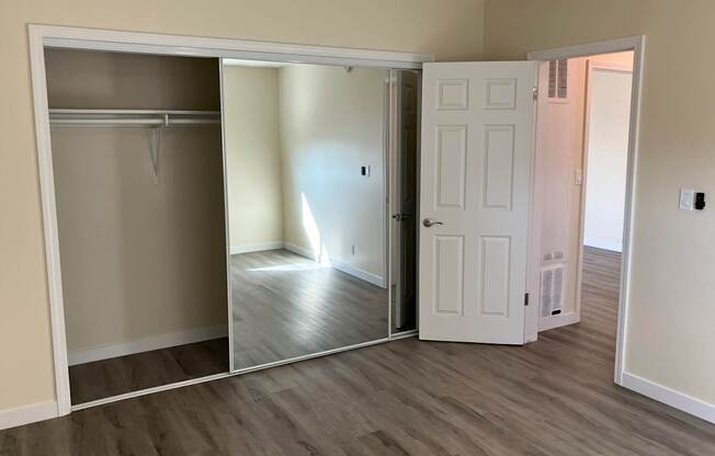 A room with a white door and a mirrored closet door.