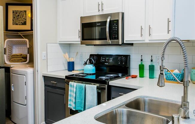 a kitchen with white cabinets and black appliances