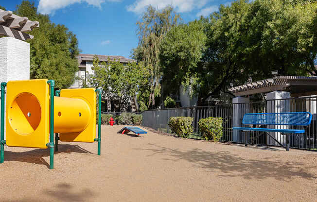 a playground with yellow and blue playground equipment and a blue bench