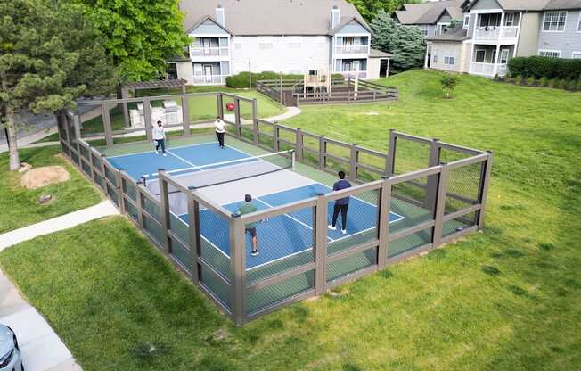 A tennis court surrounded by a fence and a grassy area.