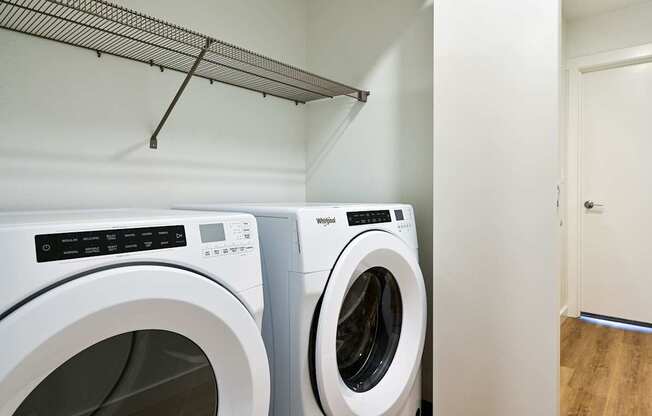 Two white front loading washing machines in a laundry room.