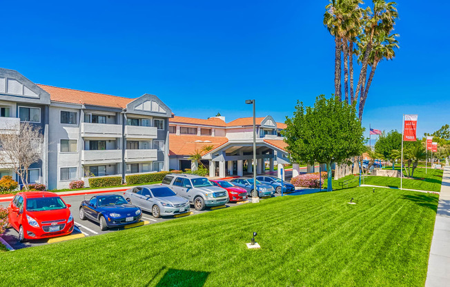 a grassy area with cars parked in front of a building