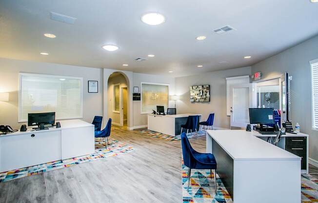 A spacious office with a white reception desk and blue chairs.