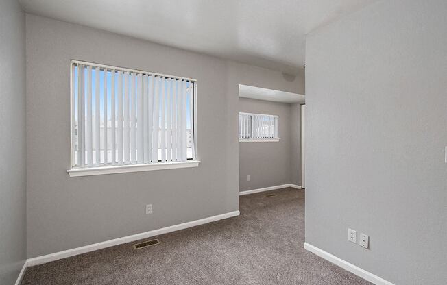 an empty bedroom with a large window and carpeted flooring