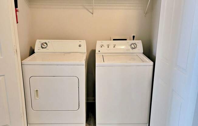 a washer and dryer in a room with wood floors and a closet