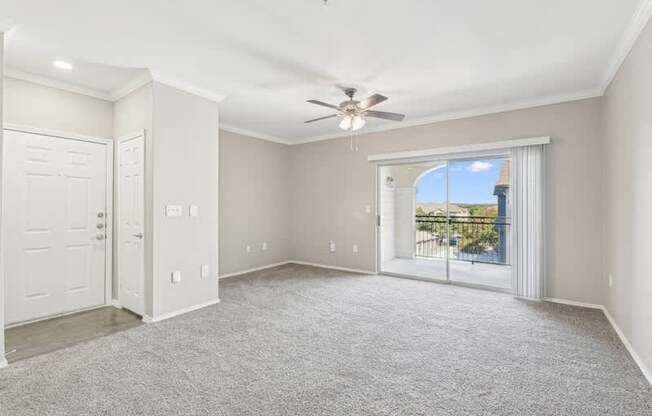 an empty living room with a ceiling fan and a window