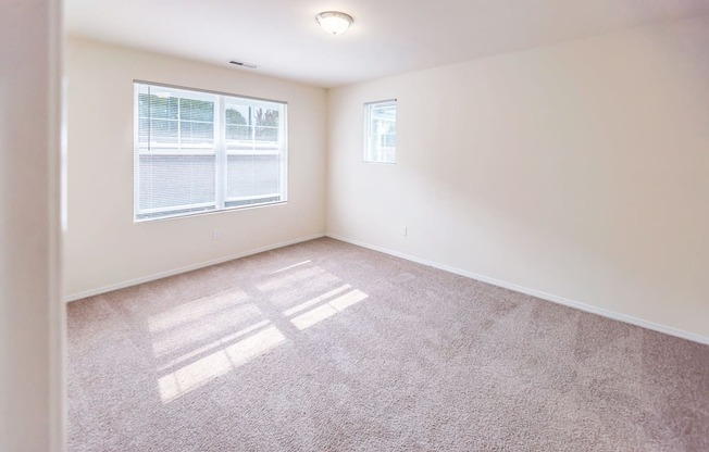 an empty living room with a window and carpet