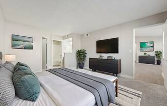 A bedroom with a large bed and a flat screen TV mounted on the wall.