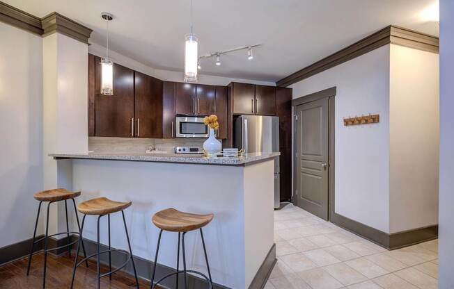 A kitchen with a white counter and brown bar stools.