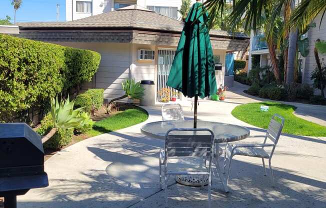 Serene courtyard at La Mesa Village apartments with barbecue and umbrella table.