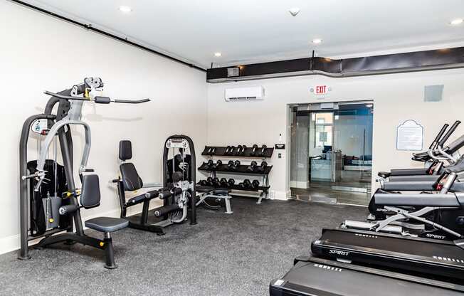 a gym with treadmills and other exercise equipment in a room with a door