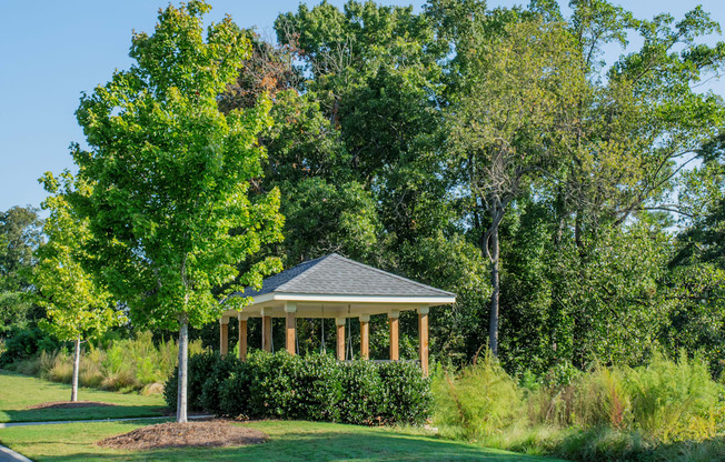 A gazebo is surrounded by greenery and trees.