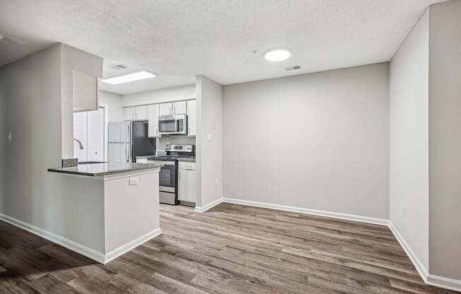 A kitchen with a refrigerator, microwave, oven, and sink.