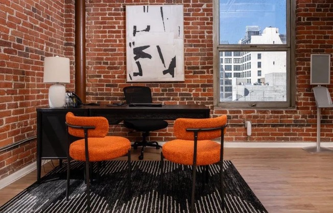 a brick walled office with a desk and orange chairs