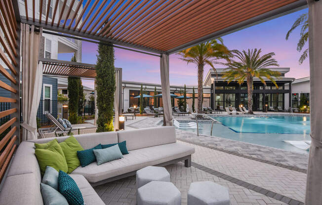 a patio with a couch and chairs and a pool in the background