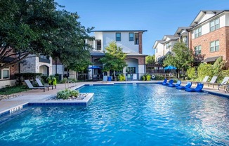 a large swimming pool with blue chairs in front of a building