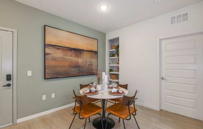 a dining room with a table and chairs and a large painting on the wall