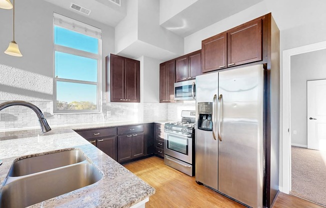A modern kitchen with a stainless steel refrigerator and a marble countertop.