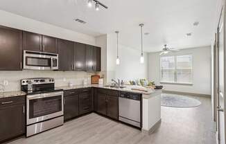 A modern kitchen with dark brown cabinets and stainless steel appliances at GreenVue Apartments in Richardson, TX