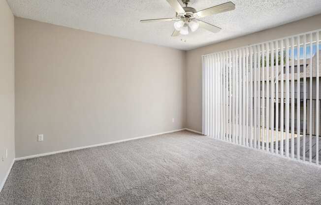 an empty bedroom with a ceiling fan and blinds