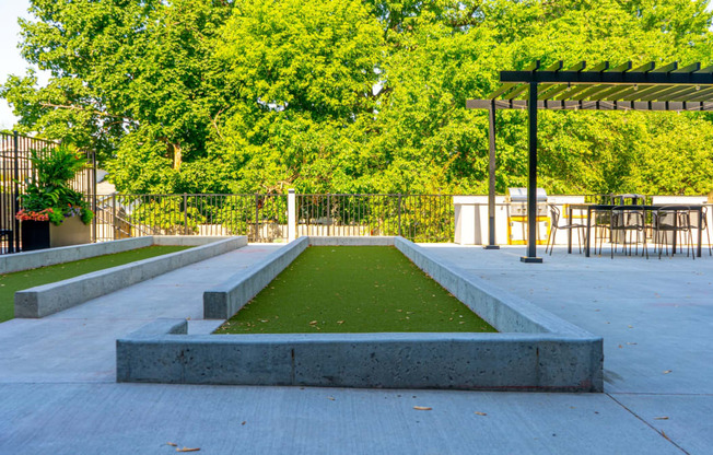 a grassy area with a pergola and tables and chairs in the background