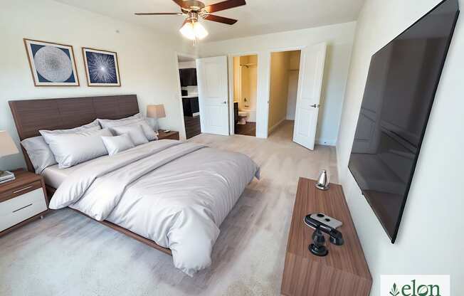 A bedroom with a large bed and a flat screen TV mounted on the wall.