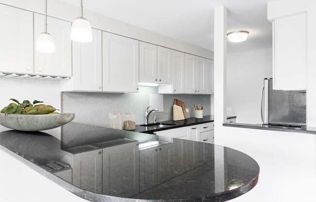 A modern kitchen with a black granite countertop and white cabinets.