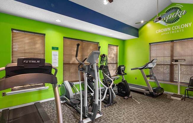 the gym is equipped with cardio equipment and green walls