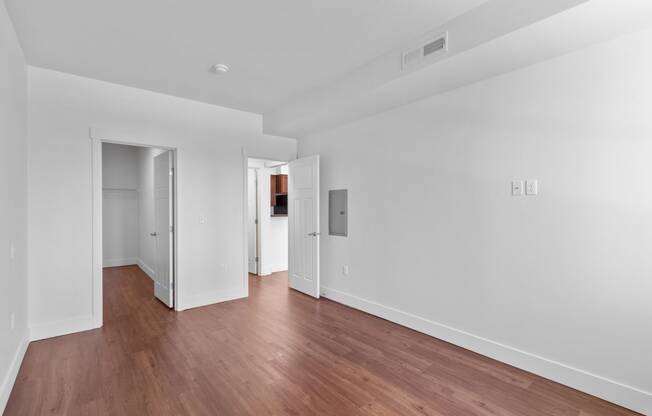 a bedroom with hardwood floors and white walls