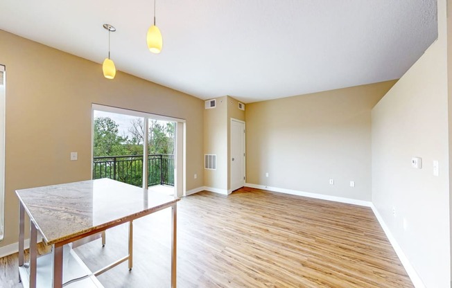 an empty living room with a glass sliding door to a balcony