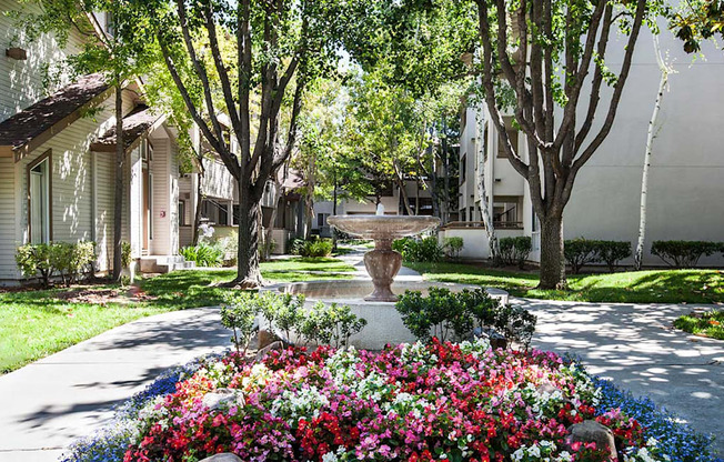 A garden with a variety of flowers in the foreground and a row of houses in the background.