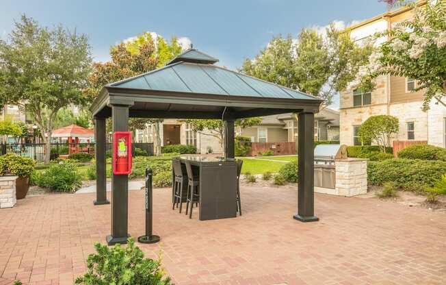 a gazebo with a table and chairs in the middle of a brick patio