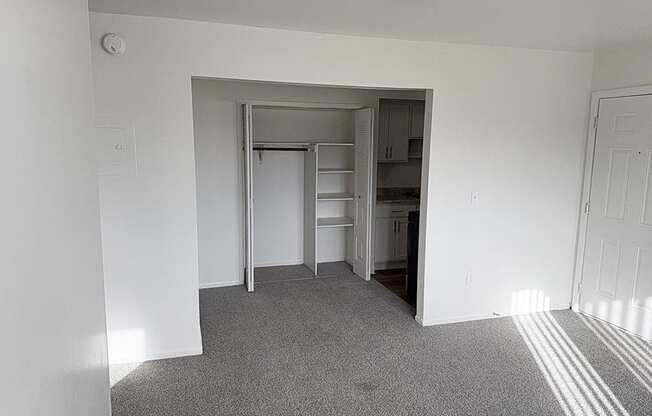 A living and dining room with a closet with shelves and carpet at Waverly Park Apartments, Lansing