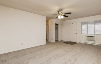 an empty living room with a ceiling fan and a window