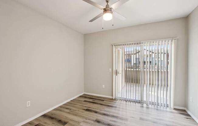 A room with a ceiling fan and sliding glass doors.