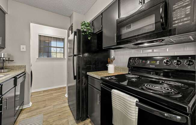 a kitchen with black appliances and a black refrigerator at Legacy Apartments in Plano, TX