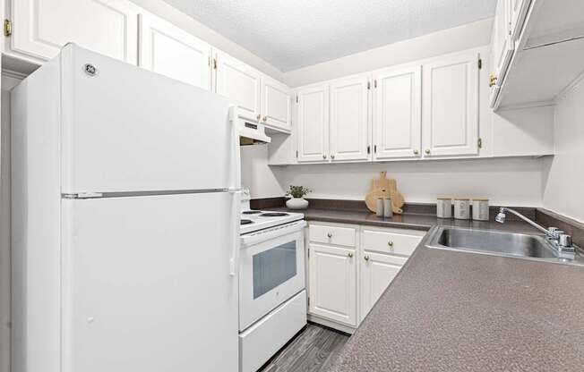 A white refrigerator is in a kitchen with white cabinets.