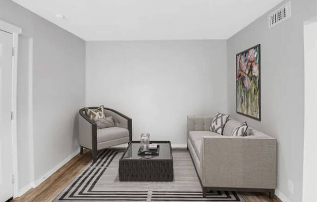 A living room with a grey sofa, a grey armchair, a black coffee table and a grey rug.